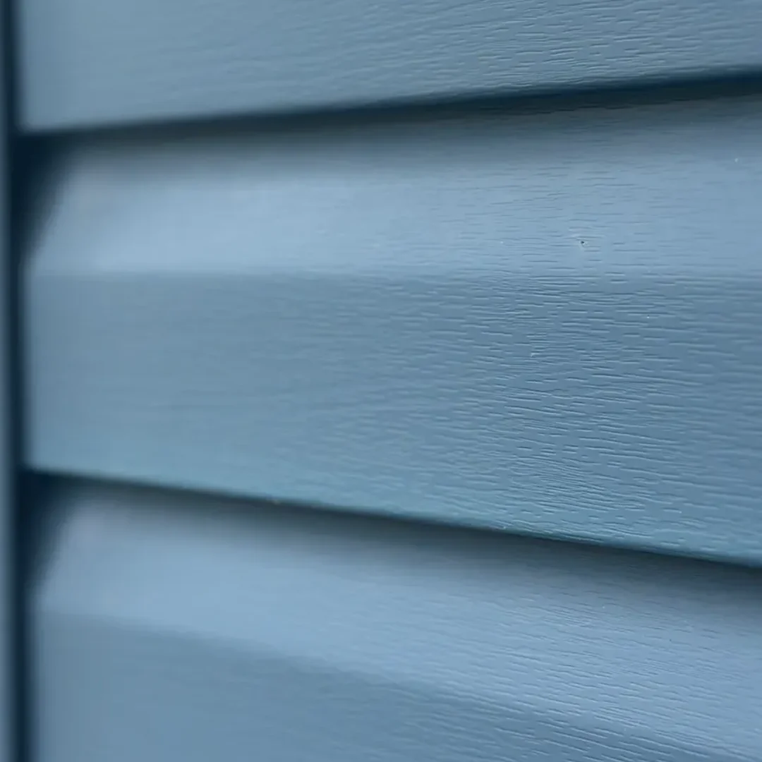 After — Oxidation removal — the chalky UV haze dissolved and hand-brushed off, the original blue back. Same siding, no paint.