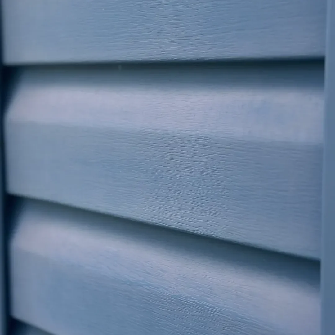 Before — Oxidation removal — the chalky UV haze dissolved and hand-brushed off, the original blue back. Same siding, no paint.