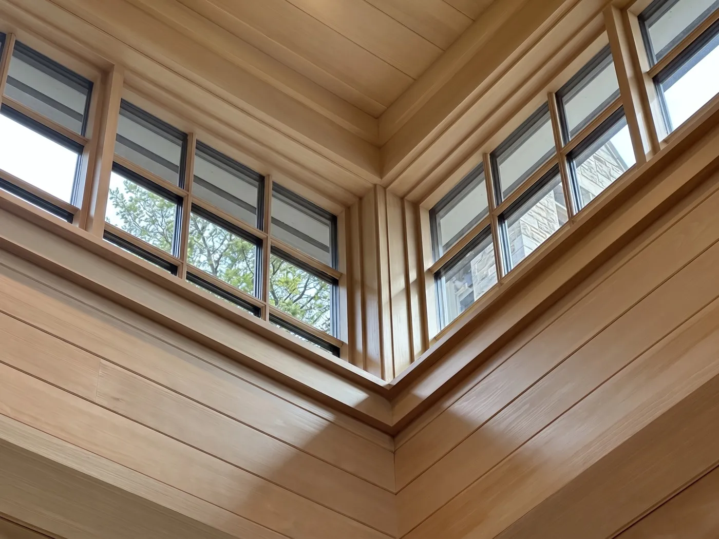 After — Divided-lite clerestories in a cedar great room — hazy, hard-water-spotted glass detailed pane by pane until it reads crisp from the floor.